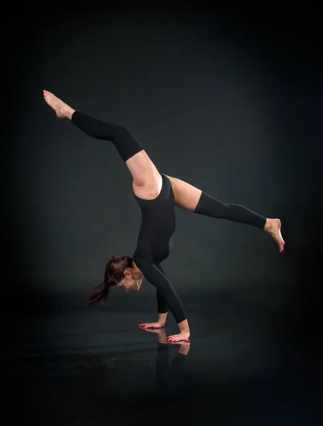girl athlete gymnast performing acrobatic elements on a black ba