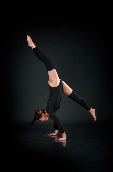 Kvinna gymnast visar atletisk skicklighet mot mörk bakgrund — Stockfoto