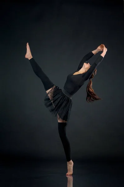 woman athlete gymnast performing acrobatic elements on a black b