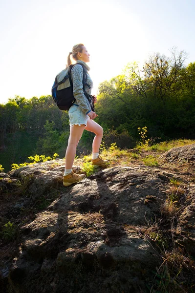 Kvinna backpacker klättring med ryggsäck i skogen på den väg du — Stockfoto