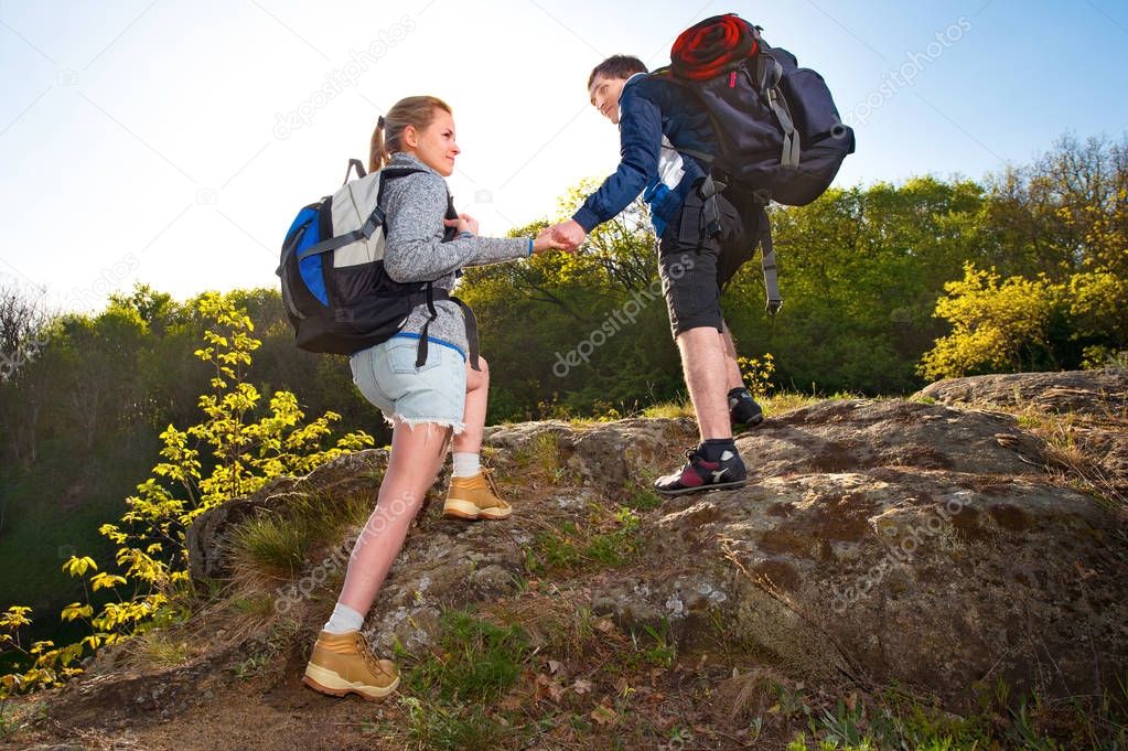 Active young backpackers traveling in the forest on light summer day. Travel, hiking, backpacking, tourism and people concept