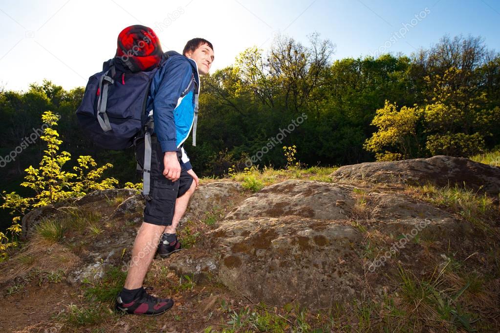 A young man backpackers hiking on the path during summer. Travel, hiking, backpacking, tourism and people concept