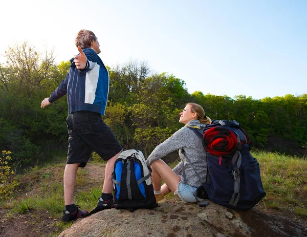 夫婦ハイカーの休憩のバックパックと 男は両手を広げて深呼吸を取る 冒険のコンセプトです 森山風景を背景 — ストック写真