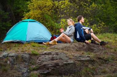 Çift vahşi ormanda hiking. Erkek ve kadın bardak çay ile dinlenme çadırın yakınında. Seyahat, tatil, tatil ve macera kavramı. Orman dağ manzara arka plan 