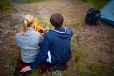 Yürüyüşçü orman, kamp, seyahat, turizm, yürüyüş ve insanlar kavramı kampında kamp ateşi yanında oturan genç aile.