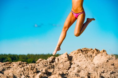 Güzel model bacakları havada kum ve mavi gökyüzü arka plan yığını üzerinde atlama, fotoğraf