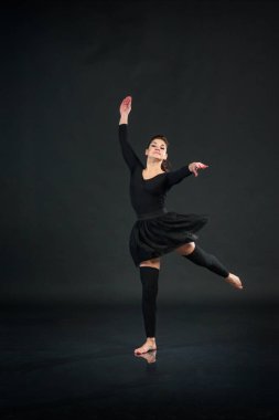 Genç kız siyah stüdyo arka plan üzerinde jimnastik egzersizleri yapıyor