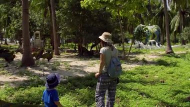 Anne ve oğlu bir bahçe hayvan heykelleri ile yürürken bir geri dönüşümlü şişe malzemelerden yapılmış. Vietnam.