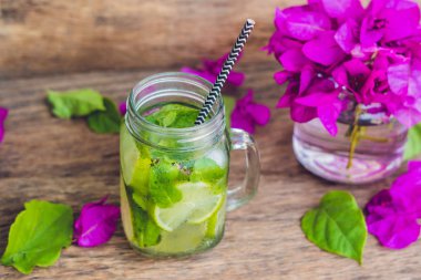 Spring purple flowers and spring mojito drink on an old wooden background clipart