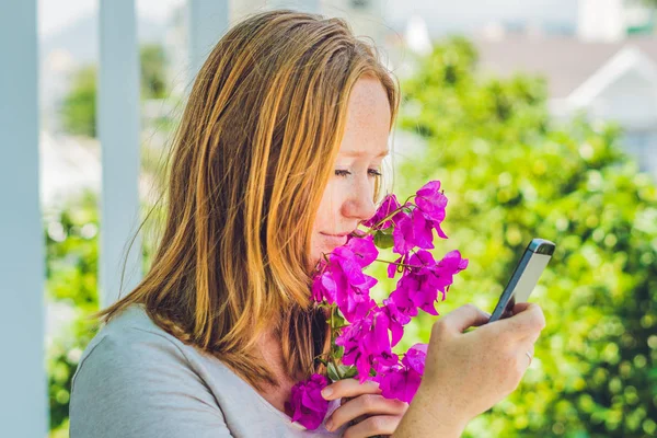 Jonge vrouw met paars Lentebloemen en met een smartphone. Lente concept — Stockfoto