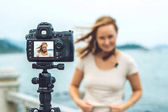 Blogger mladá žena vede její video blog před kamerou u moře. Blogger koncept