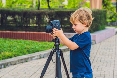 Yürümeye başlayan çocuk üzerinde bir kamera bir tripod üzerinde fotoğraf çeker
