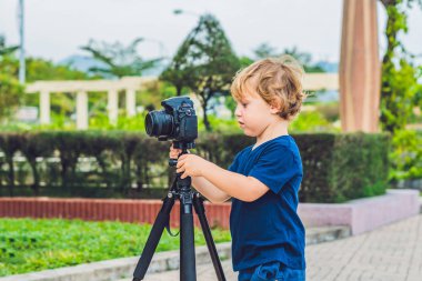 Yürümeye başlayan çocuk üzerinde bir kamera bir tripod üzerinde fotoğraf çeker