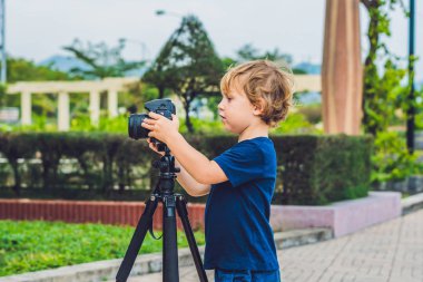 Yürümeye başlayan çocuk üzerinde bir kamera bir tripod üzerinde fotoğraf çeker