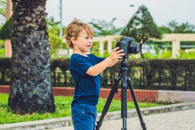 Yürümeye başlayan çocuk üzerinde bir kamera bir tripod üzerinde fotoğraf çeker