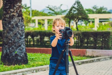 Yürümeye başlayan çocuk üzerinde bir kamera bir tripod üzerinde fotoğraf çeker