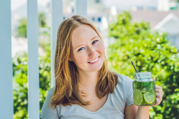 A young woman holds a mason jar in her hand with a mojito. Spring drink concept — Stock Photo, Image