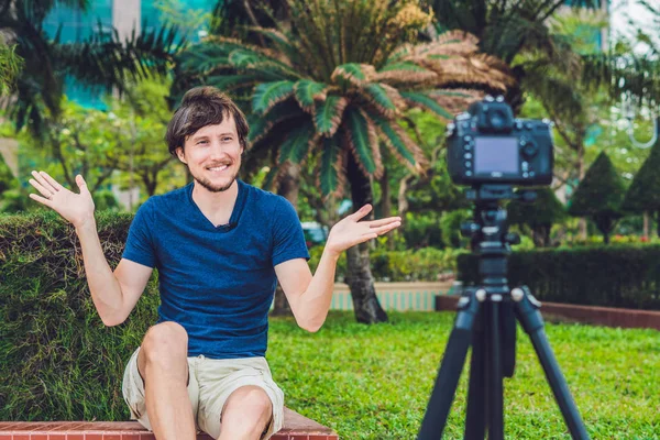 Joven bloguero graba vídeo delante de la cámara en el parque — Foto de Stock