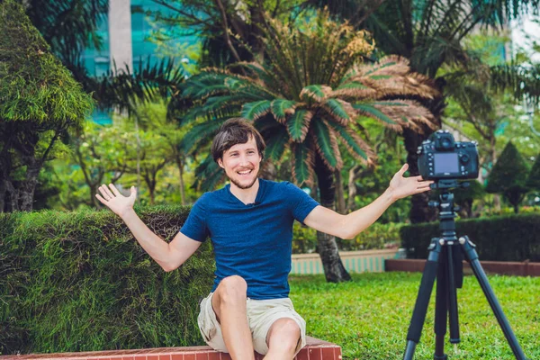 Joven bloguero graba vídeo delante de la cámara en el parque —  Fotos de Stock