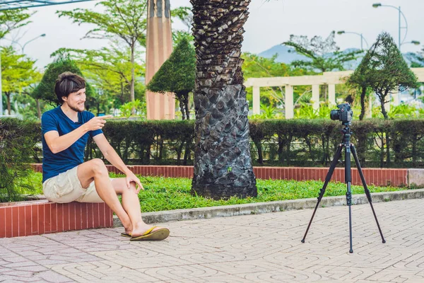Jovem blogueiro grava vídeo na frente da câmera no parque — Fotografia de Stock
