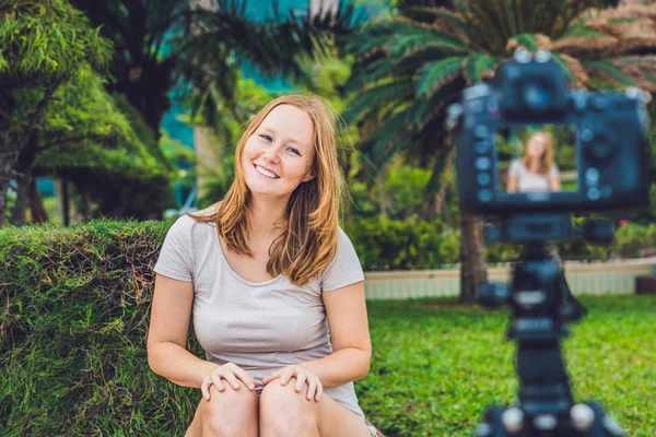 Una joven bloguera está liderando su video blog frente a la cámara en el parque. Concepto de bloguero — Foto de Stock