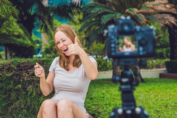 若い女性ブロガー公園でカメラの前で彼女のビデオのブログをリードしています。ブロガーのコンセプト — ストック写真