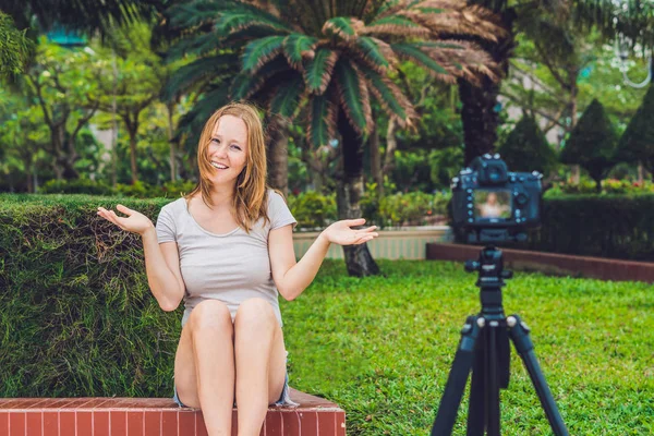 Eine junge Bloggerin führt ihren Videoblog im Park vor der Kamera. Blogger-Konzept — Stockfoto