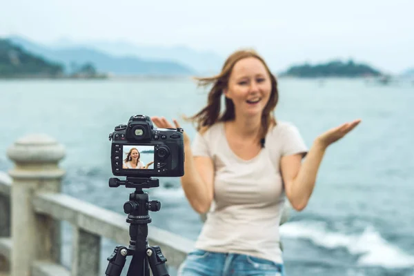 Uma jovem blogueira leva seu vídeo blog na frente de uma câmera à beira-mar. Conceito de blogueiro — Fotografia de Stock