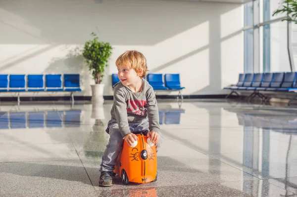 Netter kleiner Junge mit orangefarbenem Koffer — Stockfoto