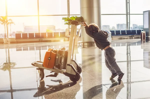 Χαριτωμένο μικρό αγόρι με πορτοκαλί βαλίτσα στο αεροδρόμιο. Το αγόρι στο τρόλεϊ και το αεροδρόμιο — Φωτογραφία Αρχείου