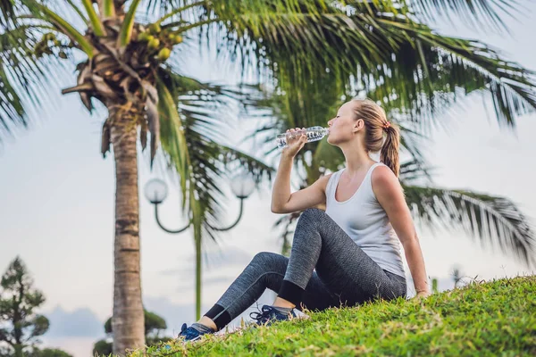 Спортивная женщина пьет воду на открытом воздухе в солнечный день — стоковое фото