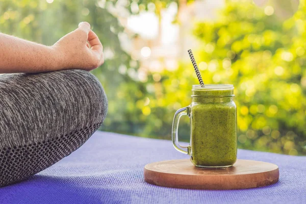 Gros plan des mains d'une femme pendant la méditation avec un smoothie vert d'épinards, d'orange et de banane — Photo