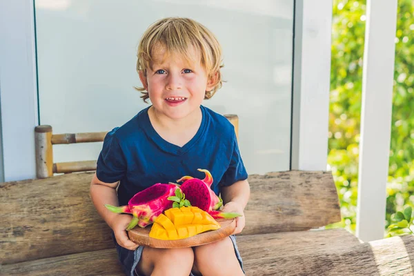 Fruta de dragón cortada en cubitos y mango en las manos del niño — Foto de Stock
