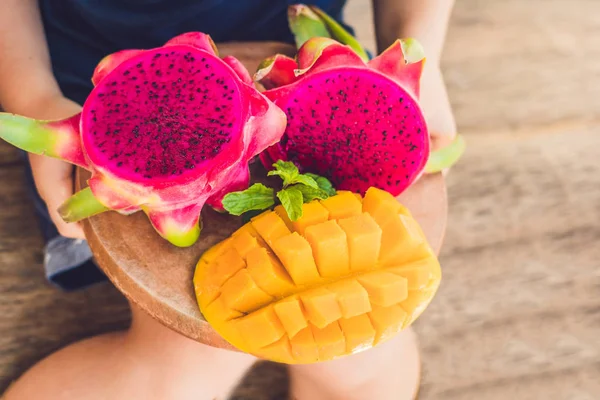 In blokjes gesneden dragon fruit en mango in de handen van de jongen — Stockfoto