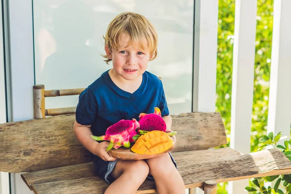 Fruta de dragón cortada en cubitos y mango en las manos del niño — Foto de Stock
