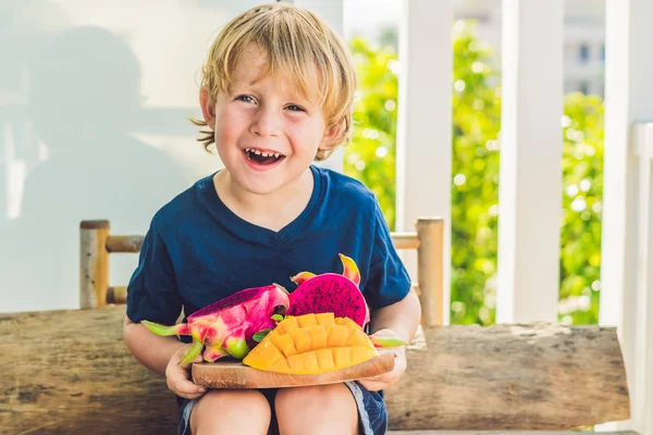 Fruta de dragón cortada en cubitos y mango en las manos del niño — Foto de Stock