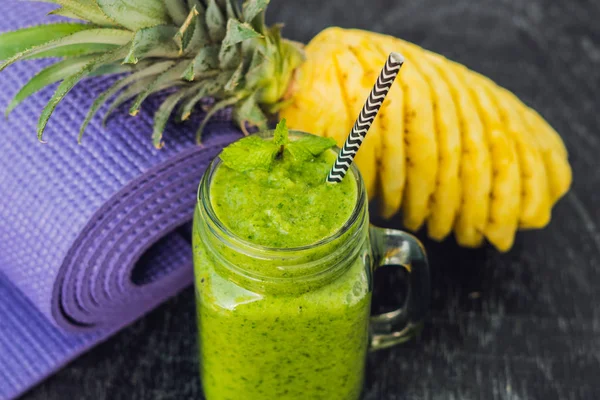 Smoothies verdes feitos de espinafre e abacaxi e um tapete de ioga. Alimentação saudável e conceito de esportes — Fotografia de Stock