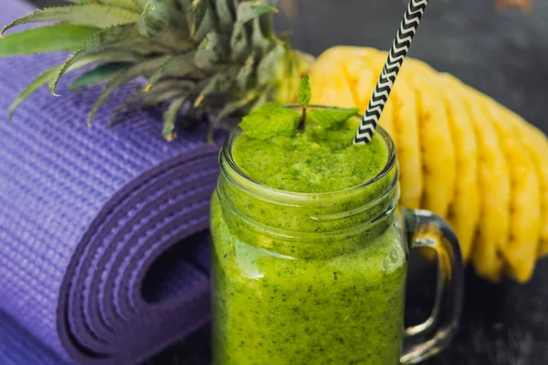 Frullati verdi fatti di spinaci e ananas e un tappetino yoga. Alimentazione sana e concetto di sport — Foto Stock