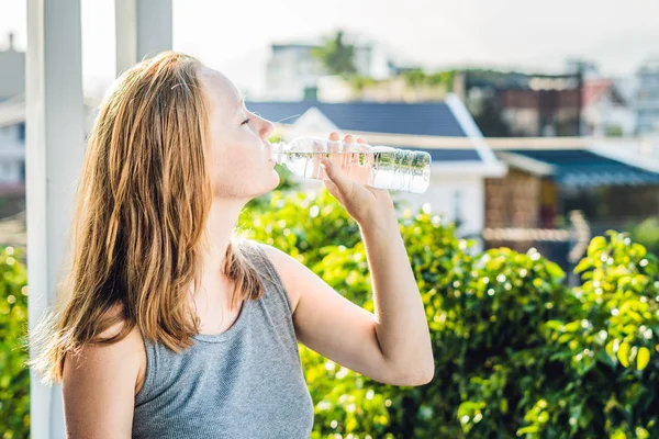 Mujer joven está bebiendo agua en el fondo del atardecer — Foto de Stock