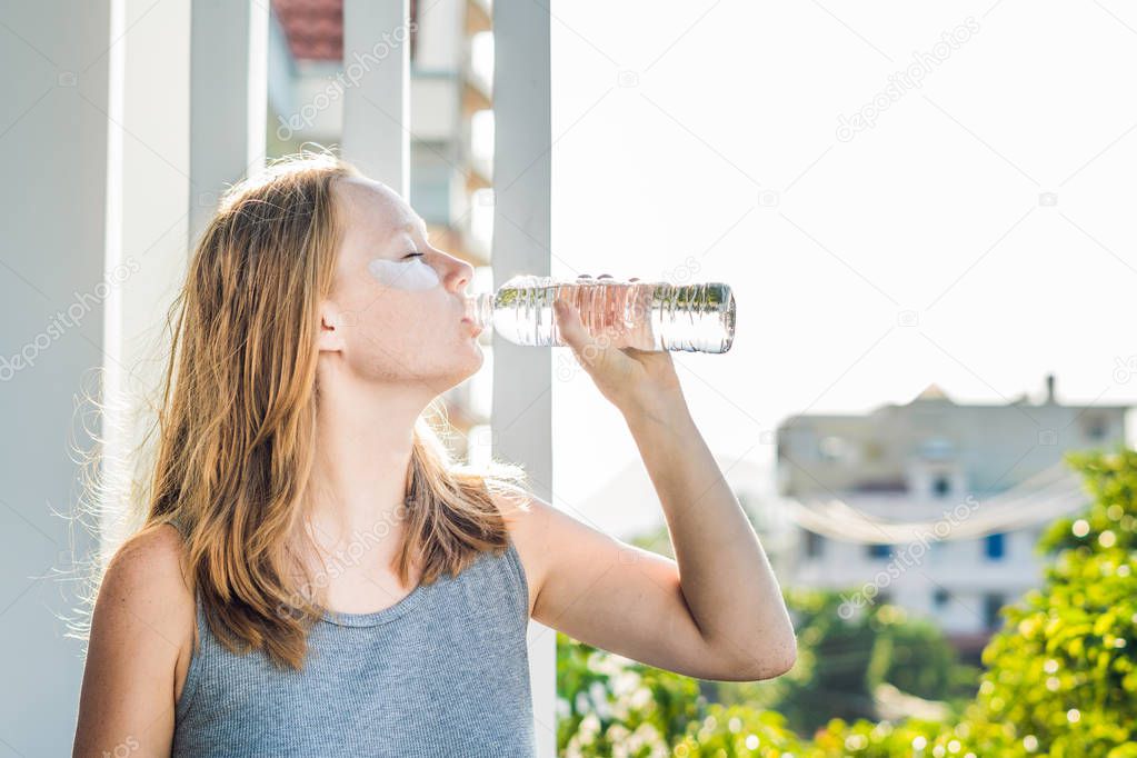 Portrait of Beauty Red-haired woman with eye patches drinks water. Spa Girl