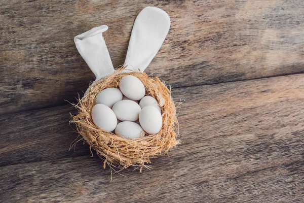 Un nido con tres huevos blancos de Pascua y orejas de conejo en casa el día de Pascua. Celebrando la Pascua en primavera. Pintura de huevos — Foto de Stock