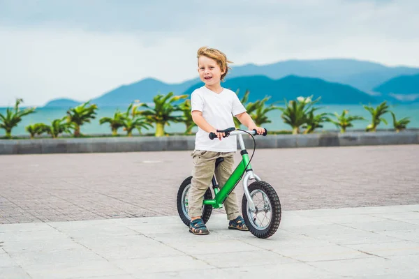 Активный блондин мальчик и велосипед у моря. Ребенок мечтает и веселится в теплый летний день. игры на открытом воздухе для детей. Концепция балансировки велосипедов — стоковое фото
