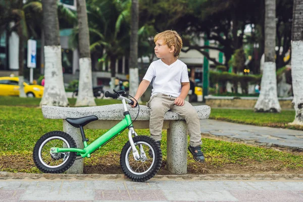 Aktiver blonder Junge und Fahrrad in der Nähe des Meeres. Kleinkind träumt und hat Spaß an warmen Sommertagen. Spiele im Freien für Kinder. Laufrad-Konzept — Stockfoto