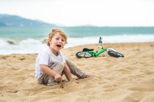 Enfant blond actif garçon et vélo près de la mer. Enfant en bas âge rêvant et s'amusant lors d'une chaude journée d'été. jeux en plein air pour les enfants. Balance concept de vélo — Photo