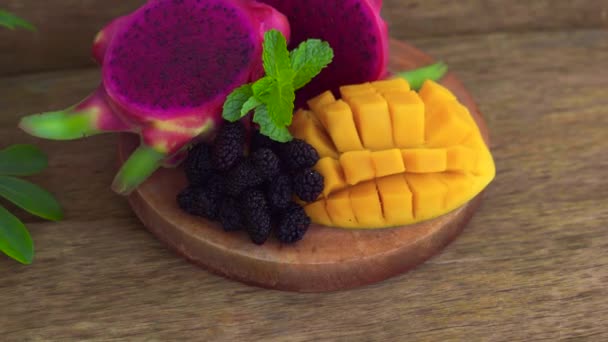 Gesneden dragon fruit en mango op een oude houten achtergrond — Stockvideo