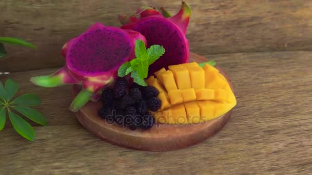 Sliced dragon fruit and mango on an old wooden background — Stock Video