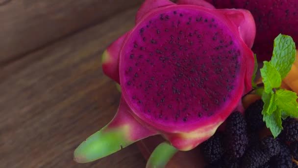 Gesneden dragon fruit en mango op een oude houten achtergrond — Stockvideo