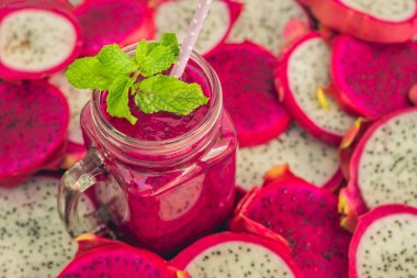 Eski bir ahşap zemin üzerinde dragon meyve parçaları ve kırmızı organik dragon meyve smoothies