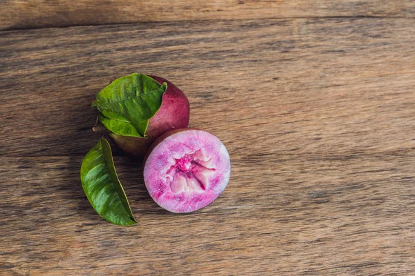 Frutti freschi di cainito Chrysophyllum su fondo legno — Foto Stock