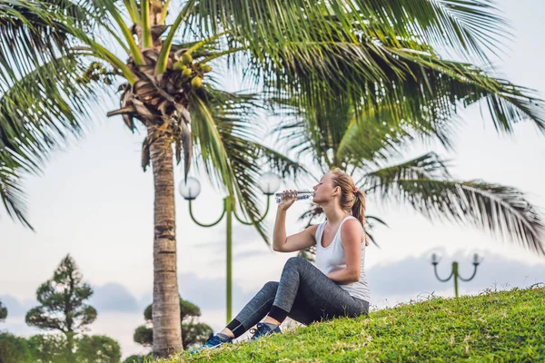 Sportliche Frau trinkt an sonnigem Tag Wasser im Freien — Stockfoto